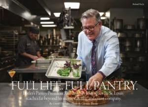 A man in a professional kitchen arranges salad leaves on a tray. He wears glasses, a white shirt, and a bright tie. Behind him, another person is preparing food. The kitchen is bustling with stainless steel equipment. Text overlays the image.